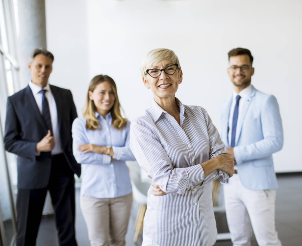 Gruppe von Geschäftsleuten, die zusammen im Büro mit ihrer reifen Businessfrau stehen - Foto, Bild