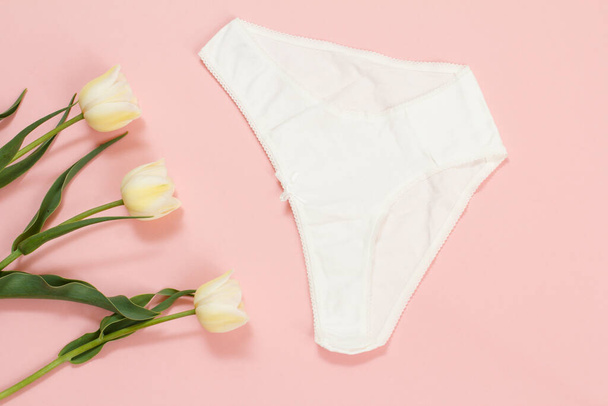 Calcinhas de algodão branco com flores de tulipa em um fundo rosa. Conjunto de cuecas femininas. Vista superior
. - Foto, Imagem