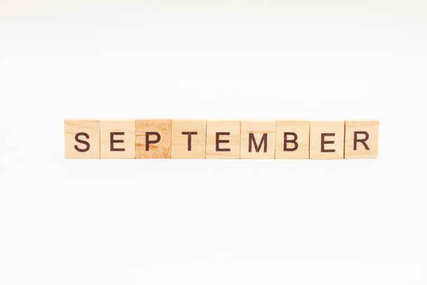 Word SEPTEMBER made of wooden blocks on white background. Month of year. First month of autumn. - Фото, изображение