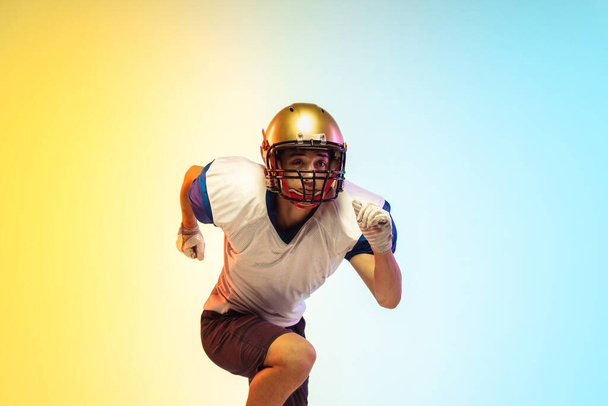 American football player isolated on gradient studio background in neon light - Фото, зображення