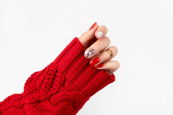 Womans hand in sweater with red manicure on gray background - Photo, Image