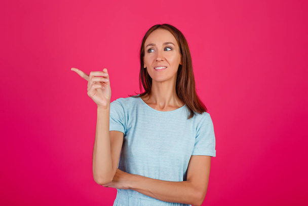 Close-up photo of an impressed lady showing hand gestures, wearing a blue t-shirt isolated on a pink background. - Foto, afbeelding
