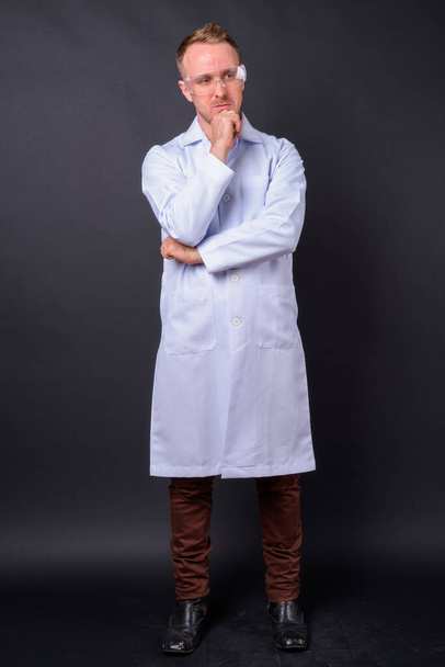 Studio laukaus komea blondi mies lääkäri tiedemies suojalasit mustaa taustaa vasten - Valokuva, kuva