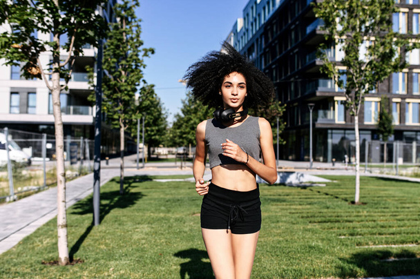An athletic girl is jogging on the city street - Фото, зображення