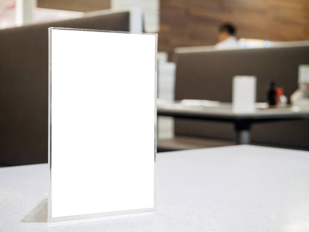 Moldura de menu Mock up na mesa no restaurante do café, suporte de acrílico com papel branco - Foto, Imagem