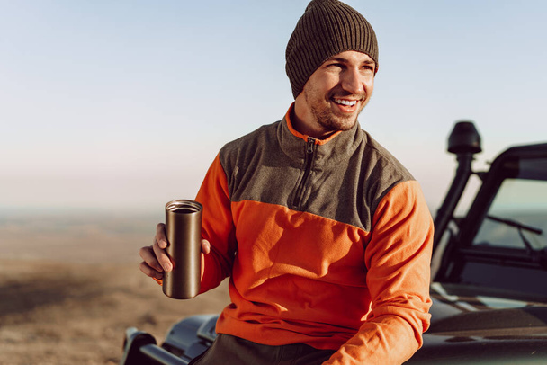 Young man traveler drinking from his thermocup while halt on a hike - Fotoğraf, Görsel