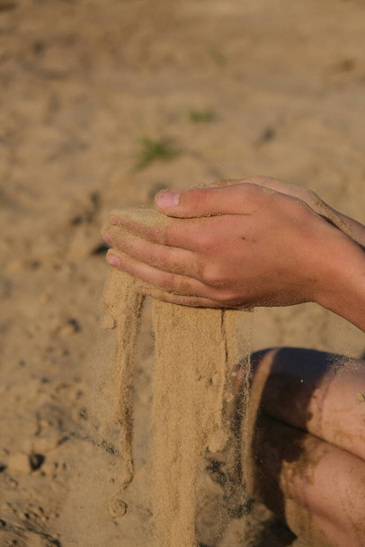 Hand clasping golden sand falling through the finger, with place for text - Фото, зображення