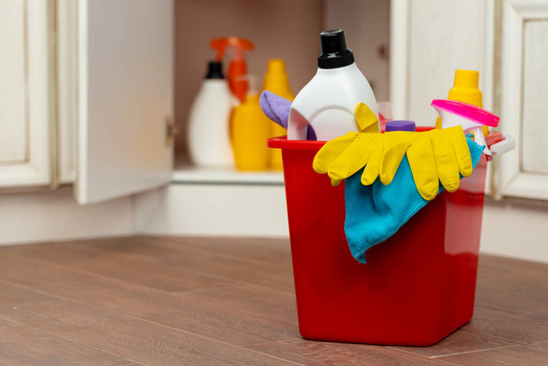 Various household cleaning detergents and bottles in a plastic bucket on the floor - Foto, Bild