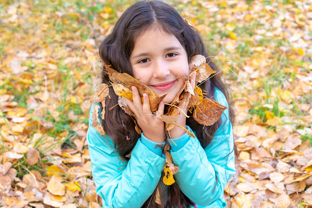 Retrato de uma menina com olhos azuis que fica na floresta de outono. Menina adolescente em um chapéu e jaqueta contra um fundo de floresta de outono amarela. Espaço para texto
 - Foto, Imagem