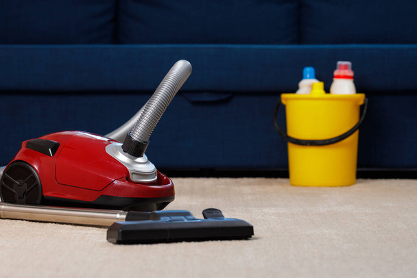 Red vacuum cleaner on a beige carpet - Фото, изображение
