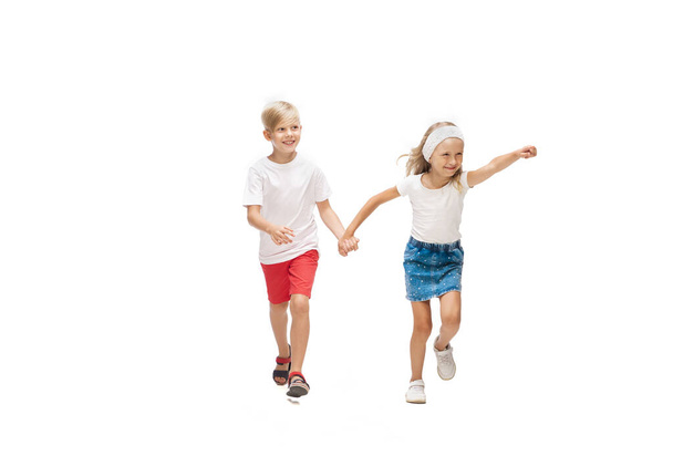 Happy little caucasian girl and boy jumping and running isolated on white background - 写真・画像