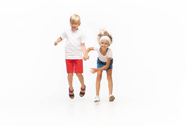Happy little caucasian girl and boy jumping and running isolated on white background - Photo, Image
