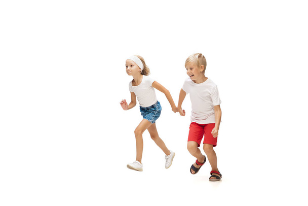 Happy little caucasian girl and boy jumping and running isolated on white background - Fotoğraf, Görsel