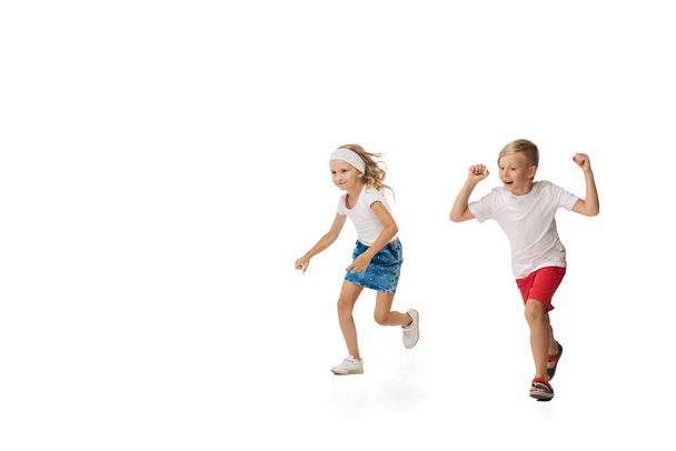 Happy little caucasian girl and boy jumping and running isolated on white background - Foto, Imagem