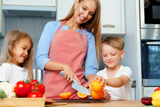 Mother cooking with her children in kitchen - Foto, Bild