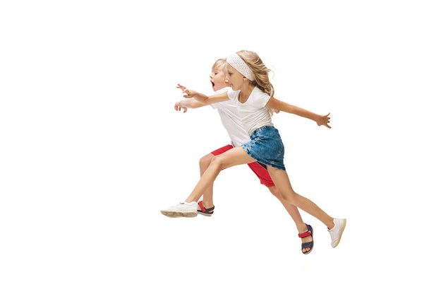Happy little caucasian girl and boy jumping and running isolated on white background - Foto, Bild