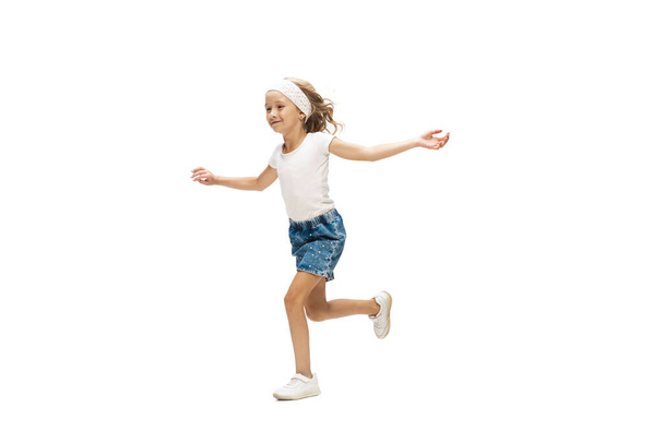Счастливая маленькая кавказская девочка прыгает и бегает изолированно на белом фоне - Фото, изображение