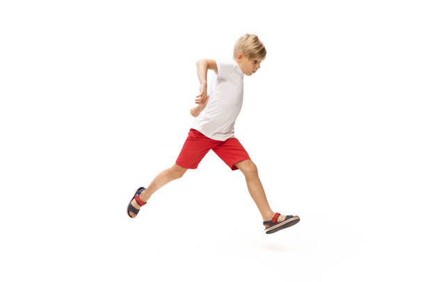 Happy little caucasian boy jumping and running isolated on white background - Zdjęcie, obraz
