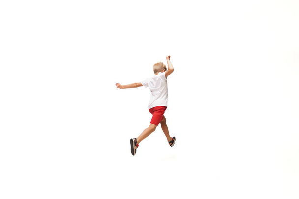 Happy little caucasian boy jumping and running isolated on white background - Фото, зображення
