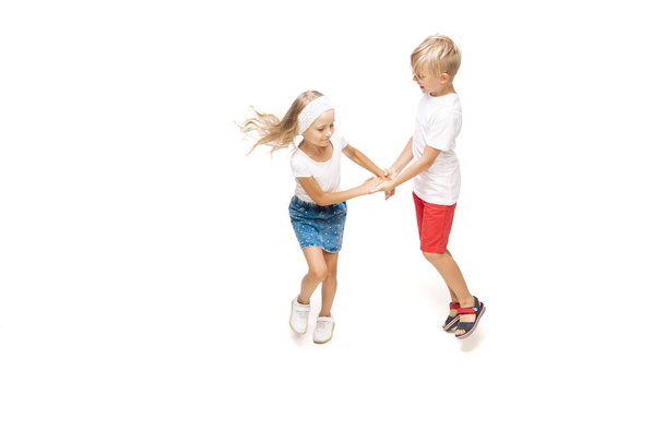 Happy little caucasian girl and boy jumping and running isolated on white background - Fotó, kép