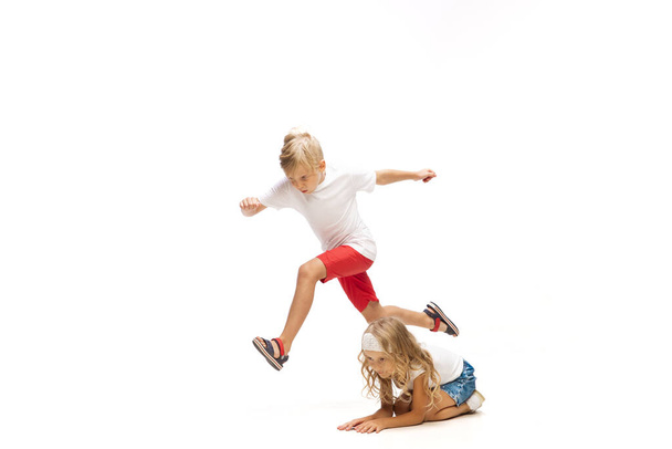 Happy little caucasian girl and boy jumping and running isolated on white background - 写真・画像