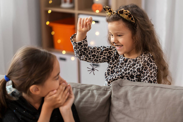 girls in halloween costumes playing with spider - Foto, Imagen