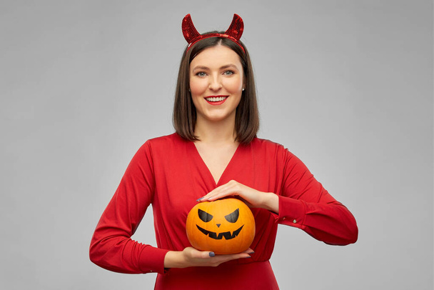 woman in halloween costume of devil with pumpkin - Foto, immagini
