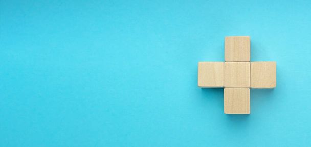 wooden blocks in the form of a cross on blue background. Success, medicine, win, victory, development or top ranking concept - 写真・画像