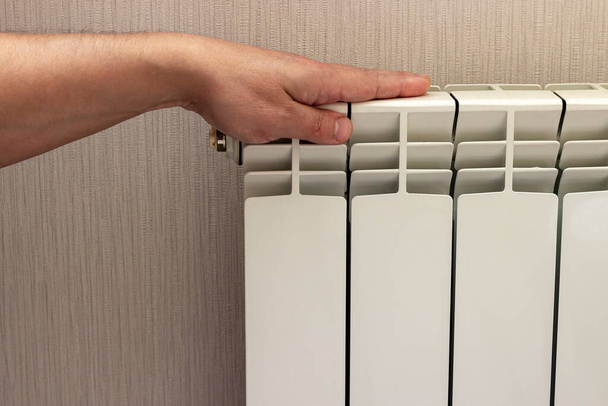 La main vérifie la température du radiateur, qu'il soit froid ou chaud. - Photo, image
