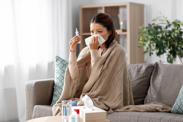 sick asian woman with nasal spray medicine at home - Fotó, kép