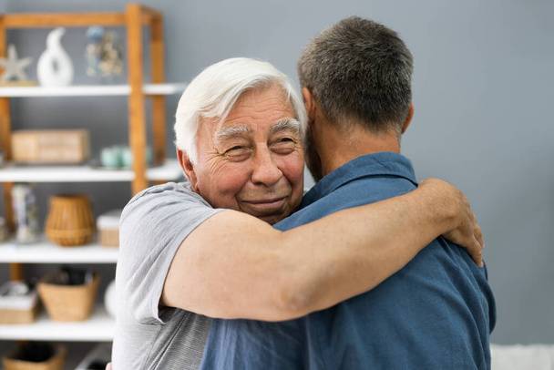 Son Hugging His Happy Senior Father Indoors - Foto, Imagen
