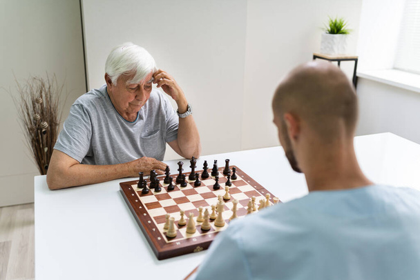 Elderly Senior Playing Chess With Caregiver At Home - Foto, Imagem