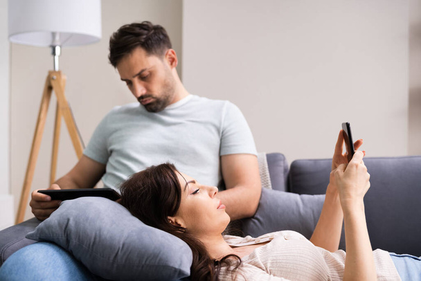 Family Couple Using Tablet And Phone On Couch - Foto, afbeelding