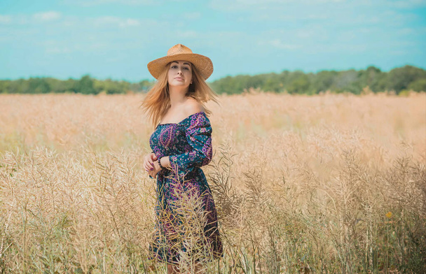 Kobieta na polu nosić rustykalny słomkowy kapelusz, boho bawełniana sukienka, moda damska - Zdjęcie, obraz