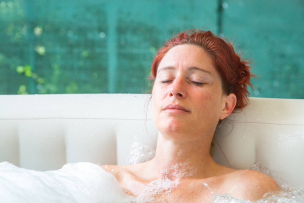 Portrait of Pretty natural redheaded woman relaxing in her jacuzzi - 写真・画像