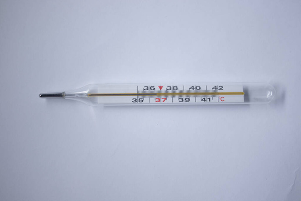 θερμόμετρο υδραργύρου σε λευκό φόντο. ιατρική και ασθένεια έννοια. Μεμονωμένα - Φωτογραφία, εικόνα