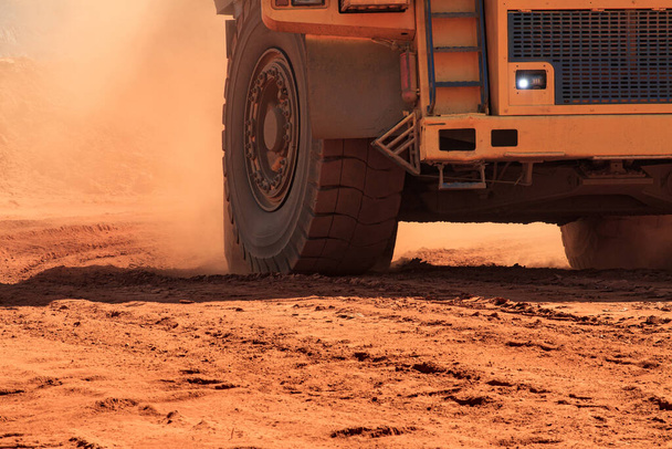 大型鉱山ダンプトラックは車輪の上にオレンジのほこりを持ち上げる - 写真・画像