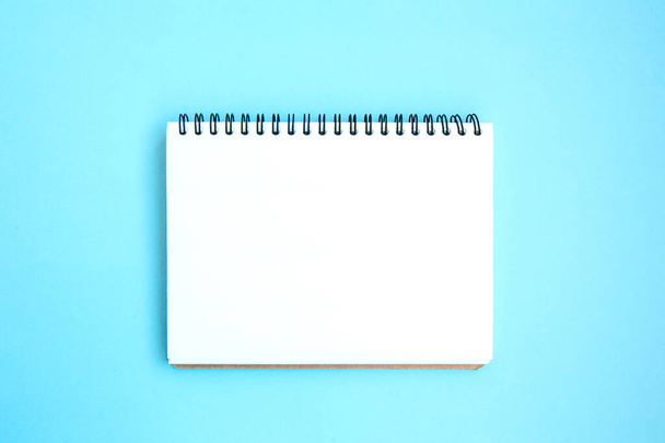 Ein weißes Notizbuch auf einer Spirale auf hellblauem Hintergrund öffnen. Leere weiße Notizblöcke. Blaues Set. Schreibwaren auf blauem Hintergrund mit Platz für Text. Minimalismus. Flache Lage - Foto, Bild