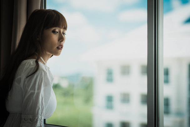 Fiatal nő áll az ablaknál otthon - Fotó, kép