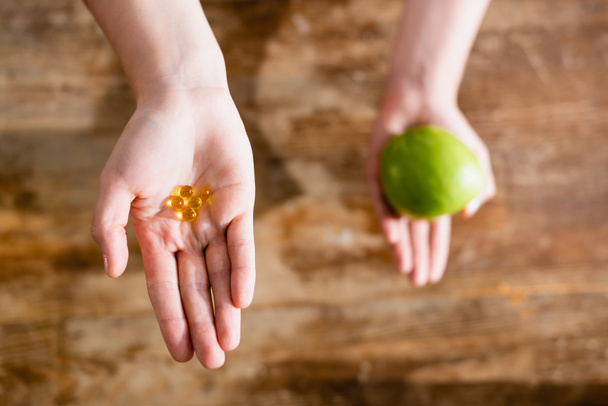 cropped view of woman holding apple and food additives in capsules  - Photo, Image