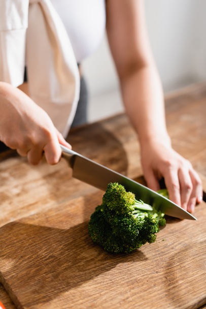 vista recortada de la mujer cortando brócoli fresco en la tabla de cortar  - Foto, Imagen