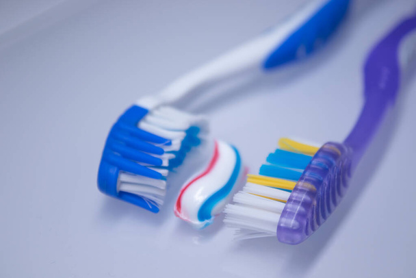 dos cepillos de dientes sobre un fondo blanco junto a la pasta de dientes. concepto de dientes sanos y limpios, odontología - Foto, Imagen