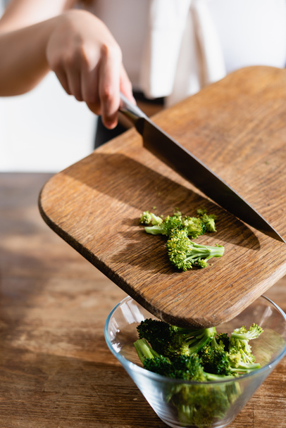 cropped view of woman adding broccoli in bowl  - Foto, afbeelding