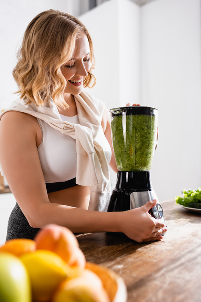 selective focus of woman mixing green smoothie in blender  - Foto, immagini