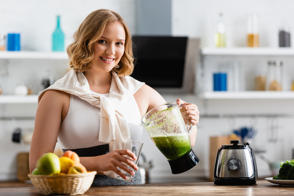 selective focus of young woman holding blender with mixed smoothie near glass  - Fotoğraf, Görsel