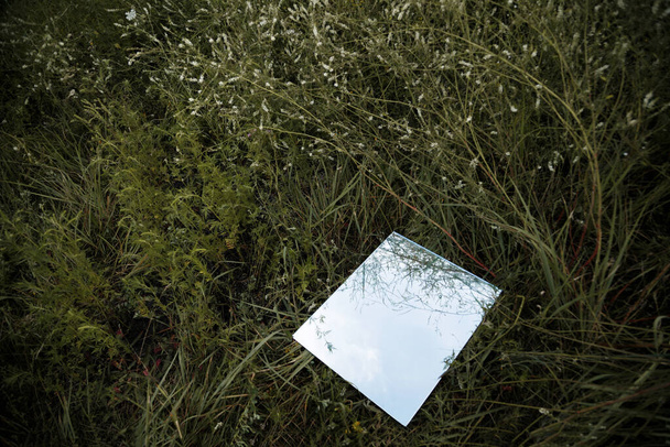 El espejo yace en la hierba verde. Reflejo del cielo - Foto, Imagen