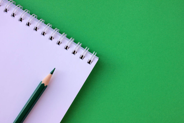 Close-up of blank notebook and pencil on green background with copy space. Back to school concept - Foto, imagen
