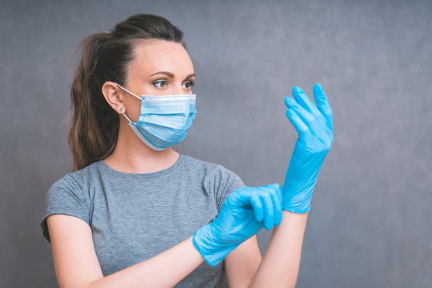 Yang woman put on blue gloves. Healthcare and Infection concept. Woman in Medical Face Mask and blue gloves against flu and viruses, copy space. - Фото, зображення