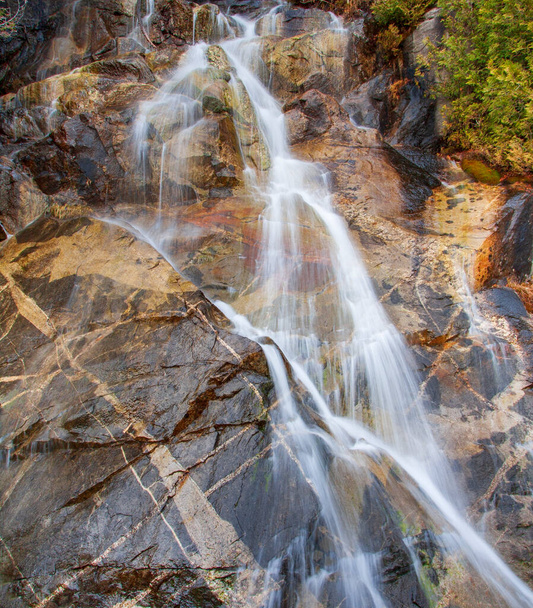 Silky water flowing over colorful rock strata with striking patterns in the stone - Photo, Image
