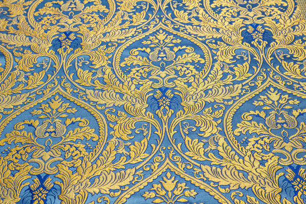 Het patroon op de stof brokaat met een herhalend patroon van bloemen en geometrische elementen.Blauwe stof kleur. Borduurwerk met metalen draden - Foto, afbeelding